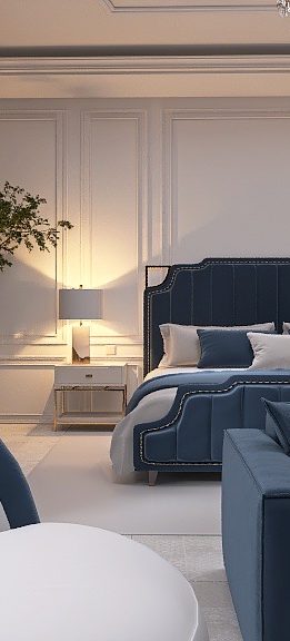 Elegante camera da letto con un grande letto con testiera blu scuro, circondato da due comodini e lampade. Ci sono alberi da interno su ogni lato. Un lampadario è appeso sopra e un divano e una sedia blu sono in primo piano.