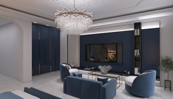 Elegante soggiorno con decorazioni blu e bianche. Presenta un lampadario moderno, una grande TV a parete, poltrone circolari, un elegante divano blu e un tavolino da caffè in vetro. Mensole integrate e una pianta in vaso aggiungono raffinatezza allo spazio.