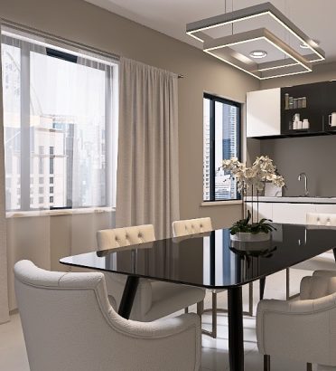 Moderna cucina e sala da pranzo con un elegante tavolo nero, sei sedie bianche imbottite e luci a sospensione. Mobili color crema, una finestra con tende leggere ed elettrodomestici da incasso creano un look contemporaneo.